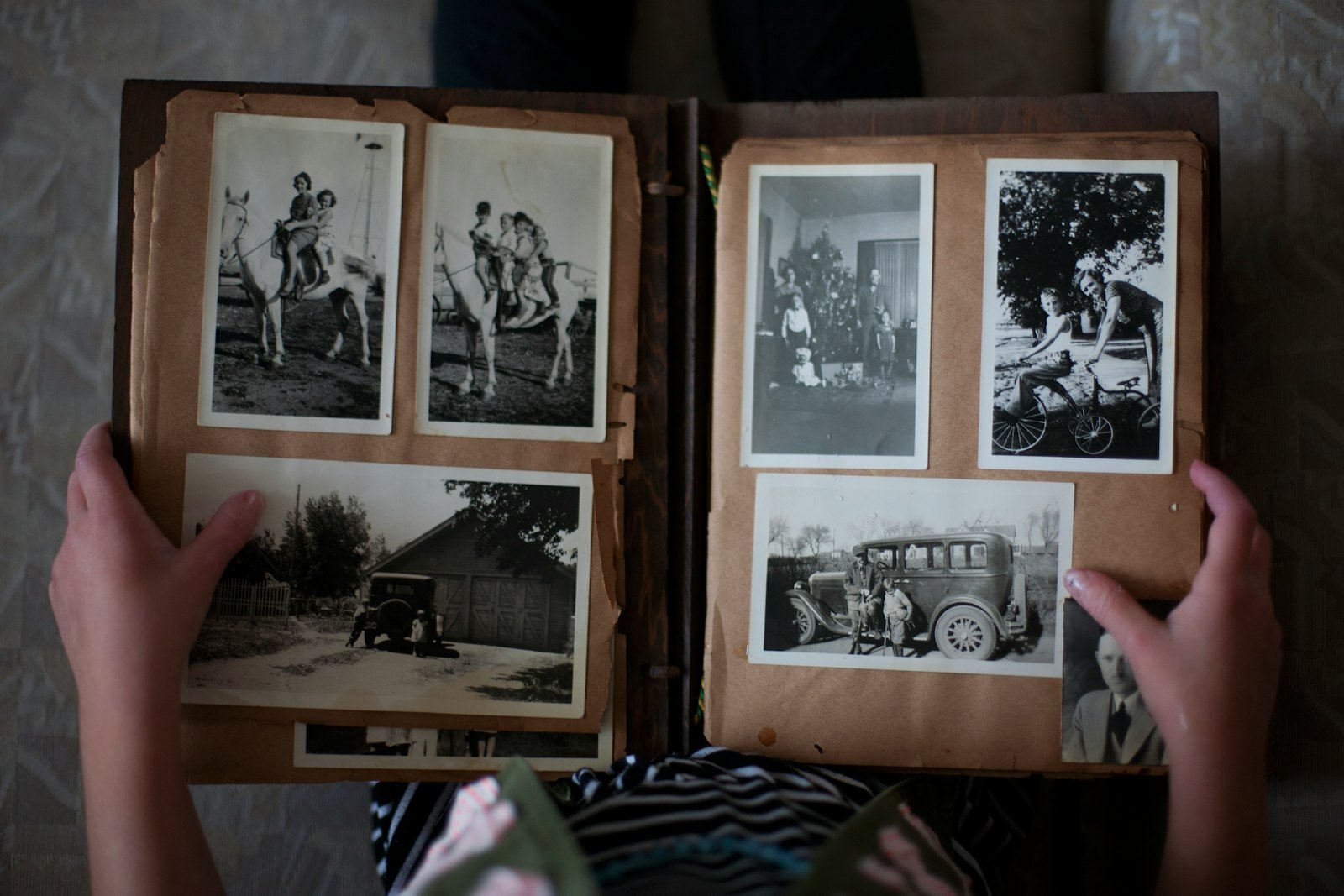 Hands opening an old family photo album full of black and white photographs